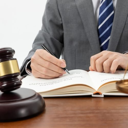 closeup-shot-person-writing-book-with-gavel-table
